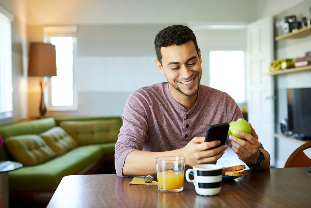 Young man having breakfast and browsing on his phone