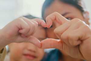 Happy mom and child making heart hands